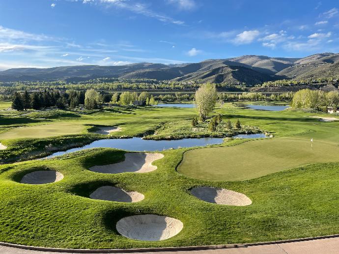 green grass field near green trees and mountains under blue sky during daytime